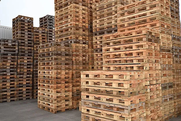 Used pallets stacked in the yard, waiting to be checked and repaired.