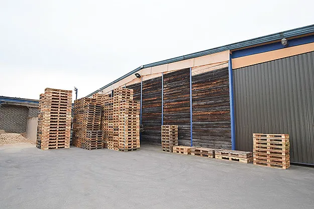 The yard with the hall and pallet stacks, seen from outside.